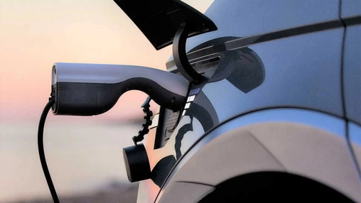 Electric vehicle plugged in using bidirectional charger at sunset