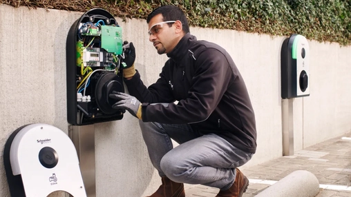 Technician inspecting internal components of an EV charger outdoors.