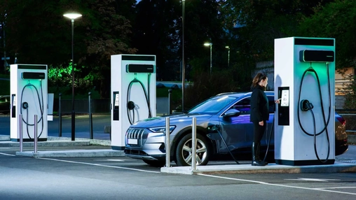 Electric car charging at modern EV fast-charging station at night