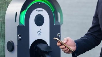 Schneider Electric EV charger with user holding a phone to activate charging