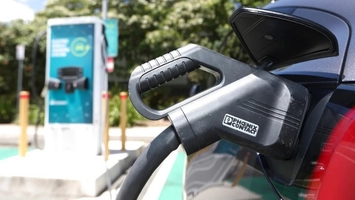 Fast charging cable plugged into electric vehicle at public EV charging station