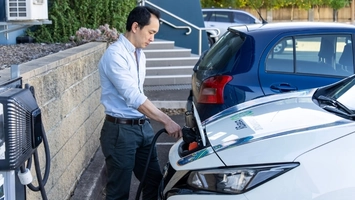 Driver plugging an electric car into a home charging unit