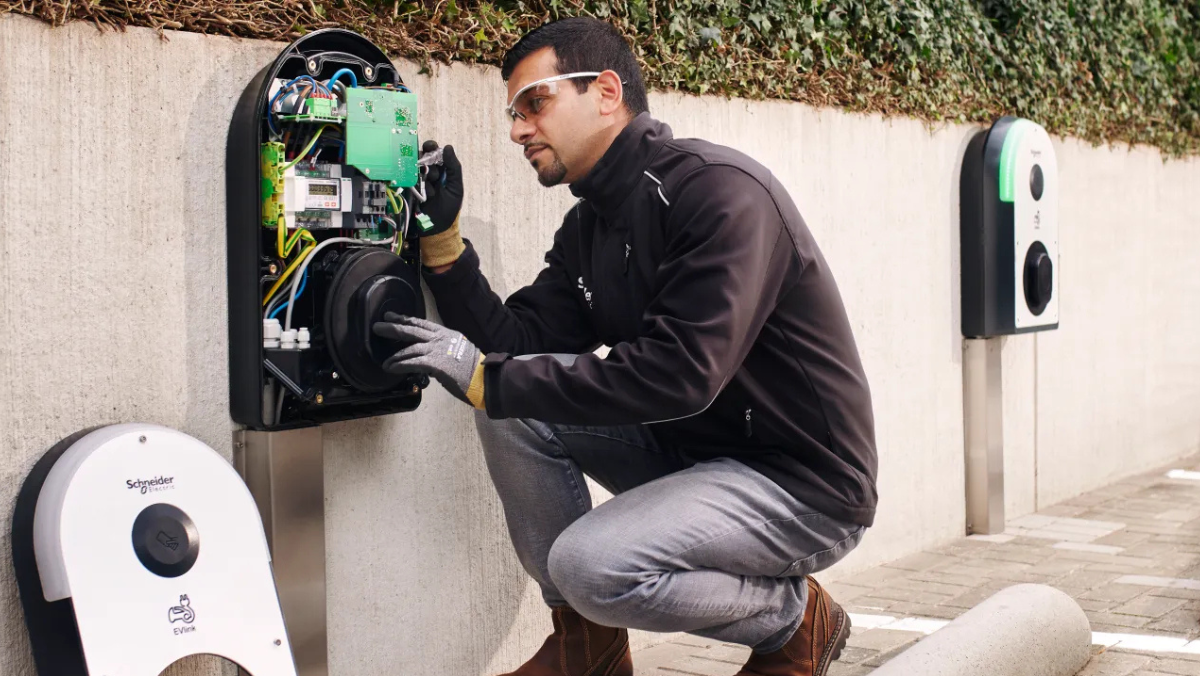 Technician inspecting internal components of an EV charger outdoors.