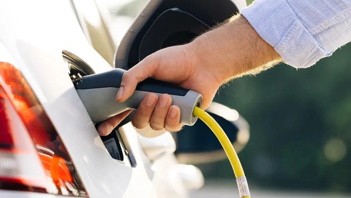 Hand plugging charging cable into electric vehicle for smart charging