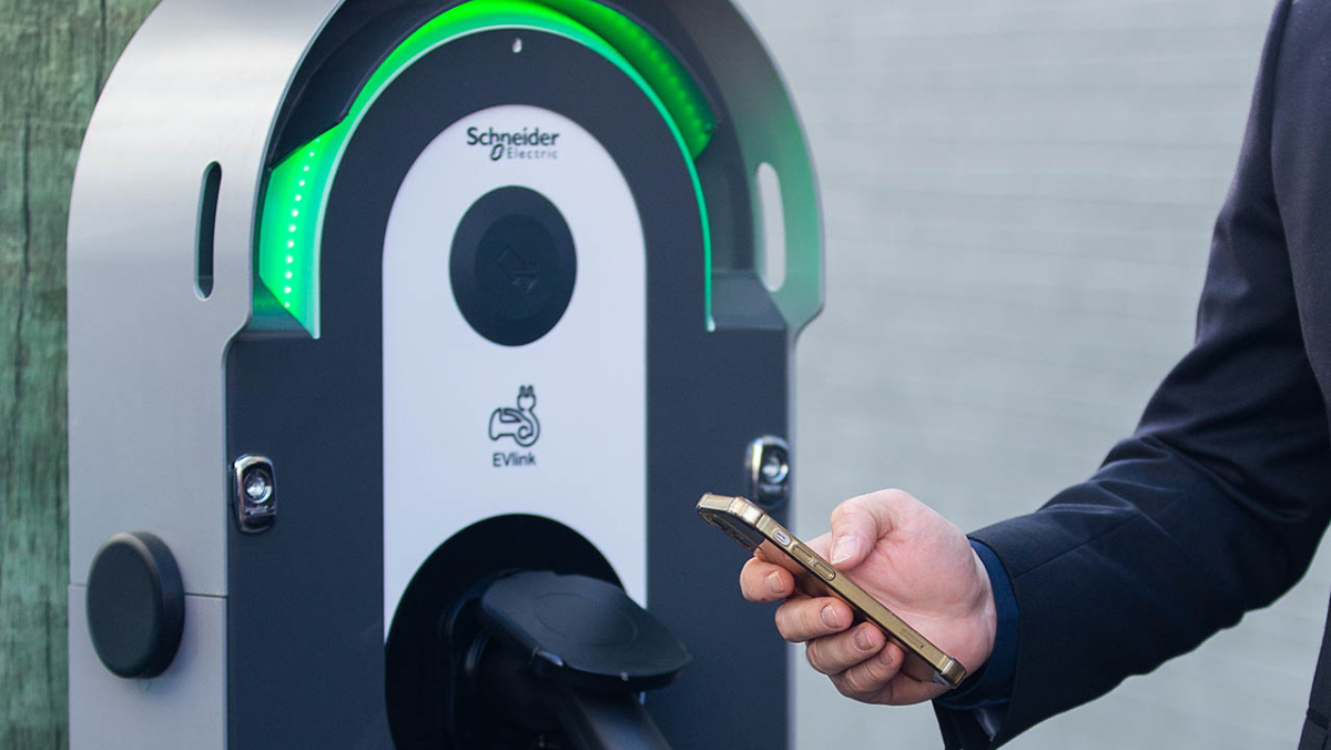 Schneider Electric EV charger with user holding a phone to activate charging