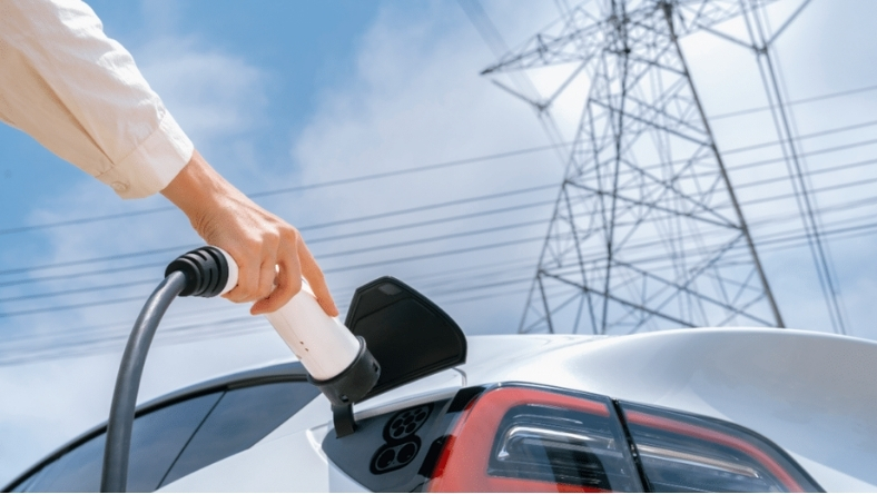 EV charging cable connected to electric car with power grid overhead